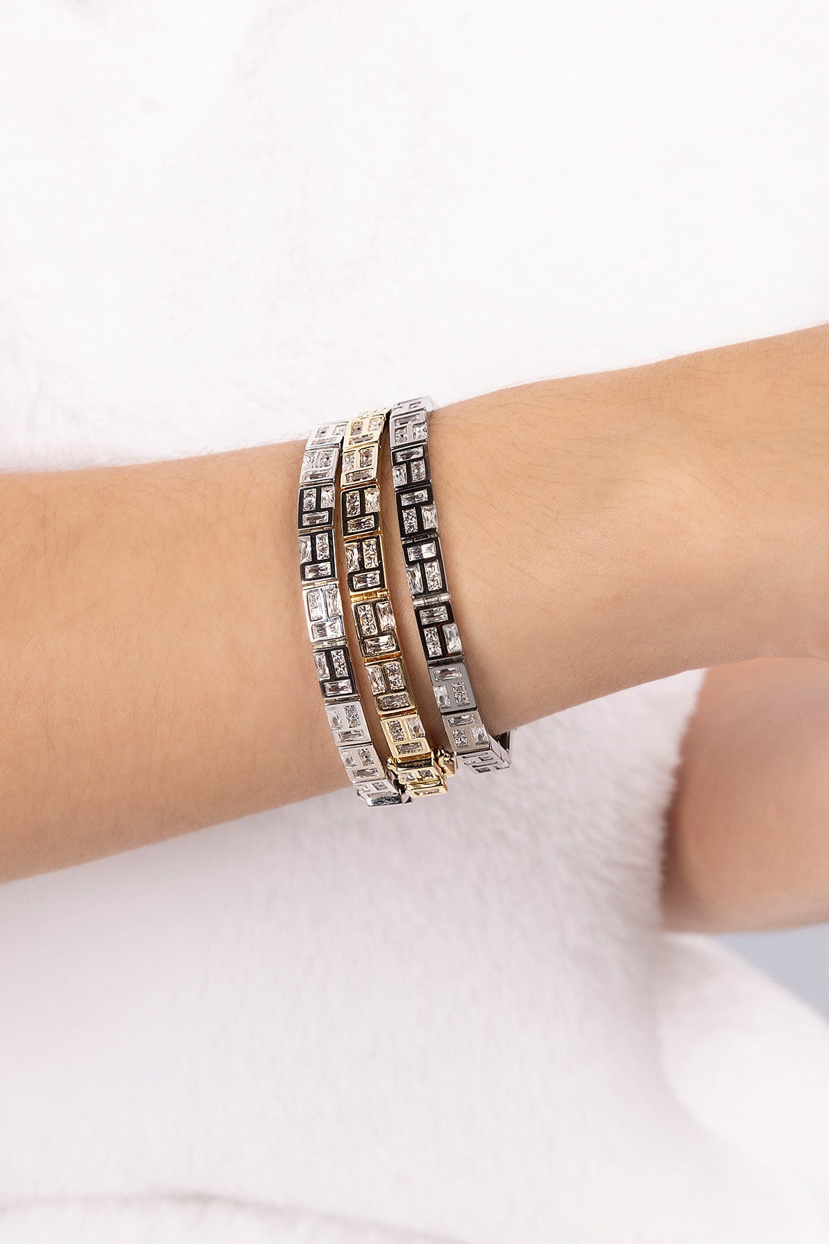 Three APM MONACO silver labyrinth bracelets on a wrist against a white background