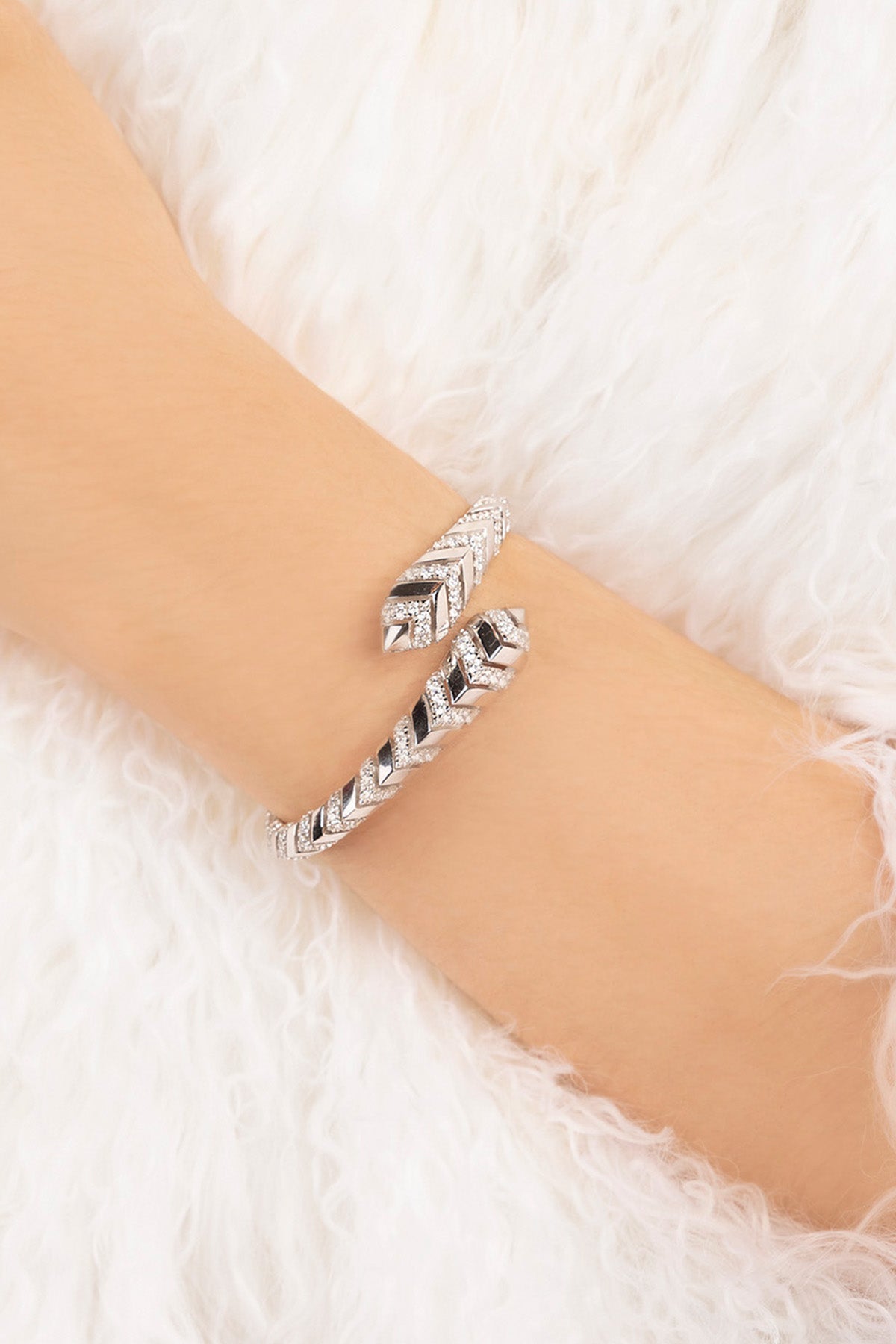 Silver bracelet on a wrist with a white textured background