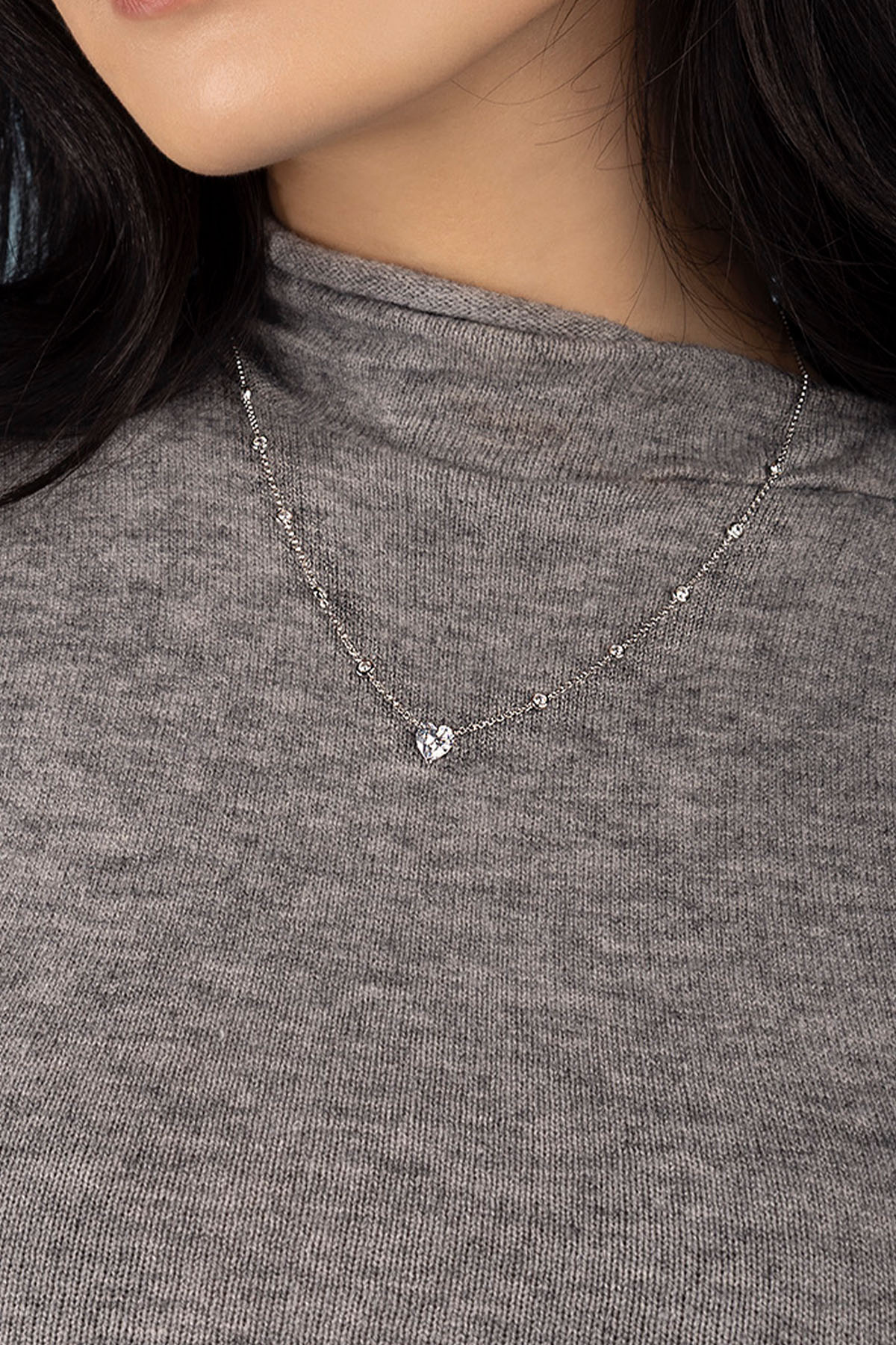 Necklace with a heart pendant worn by a model in a gray shirt