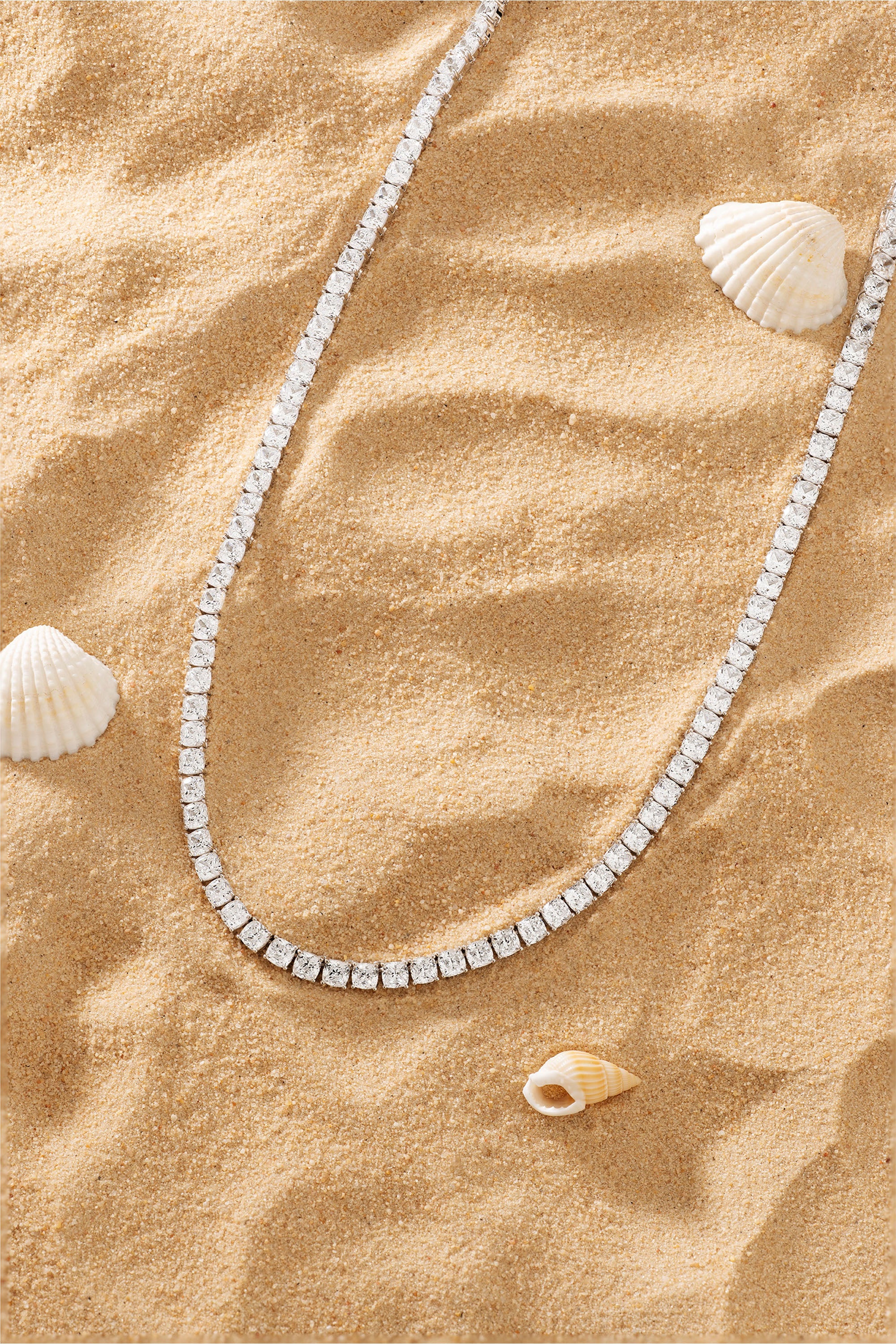 Sterling silver pavé choker necklace on sand with seashells