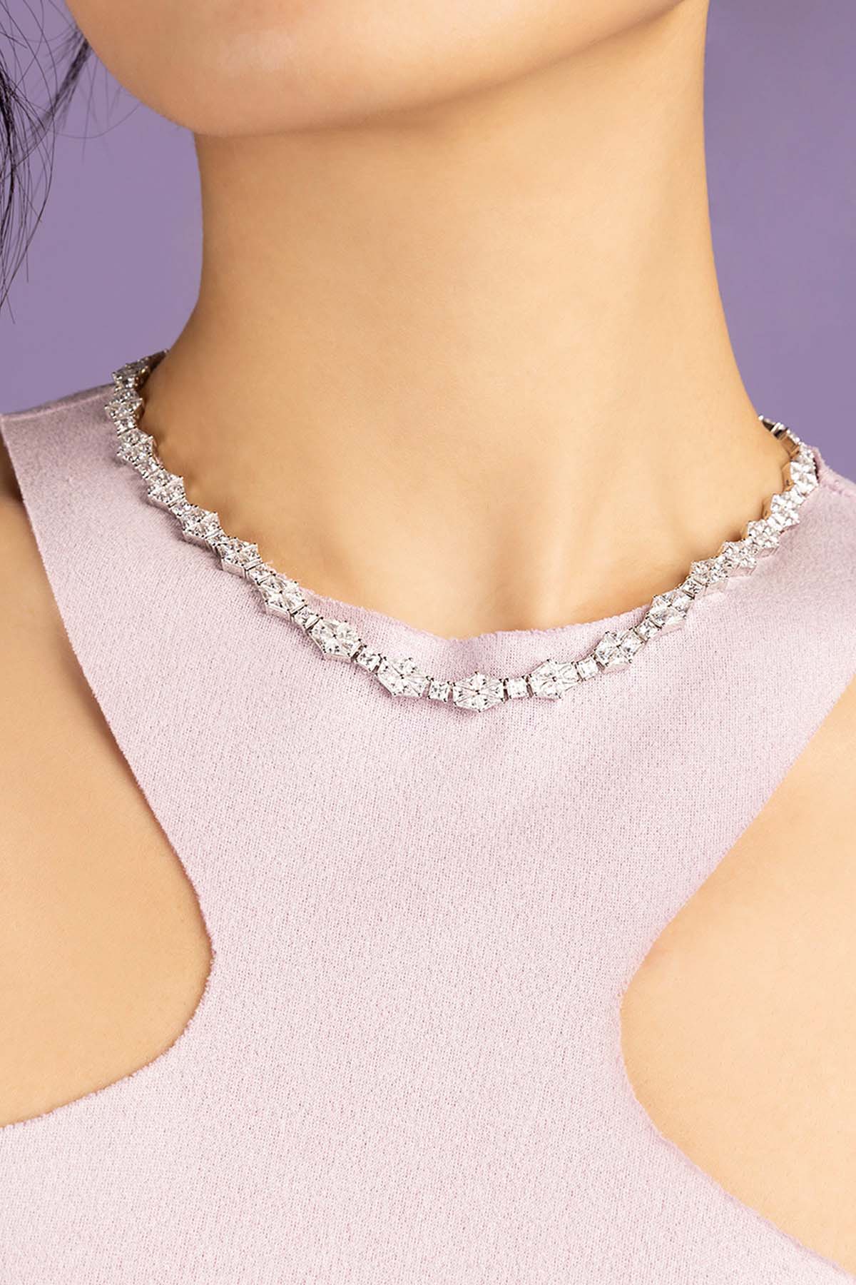 Necklace with art deco design on a person wearing a light purple top against a purple background