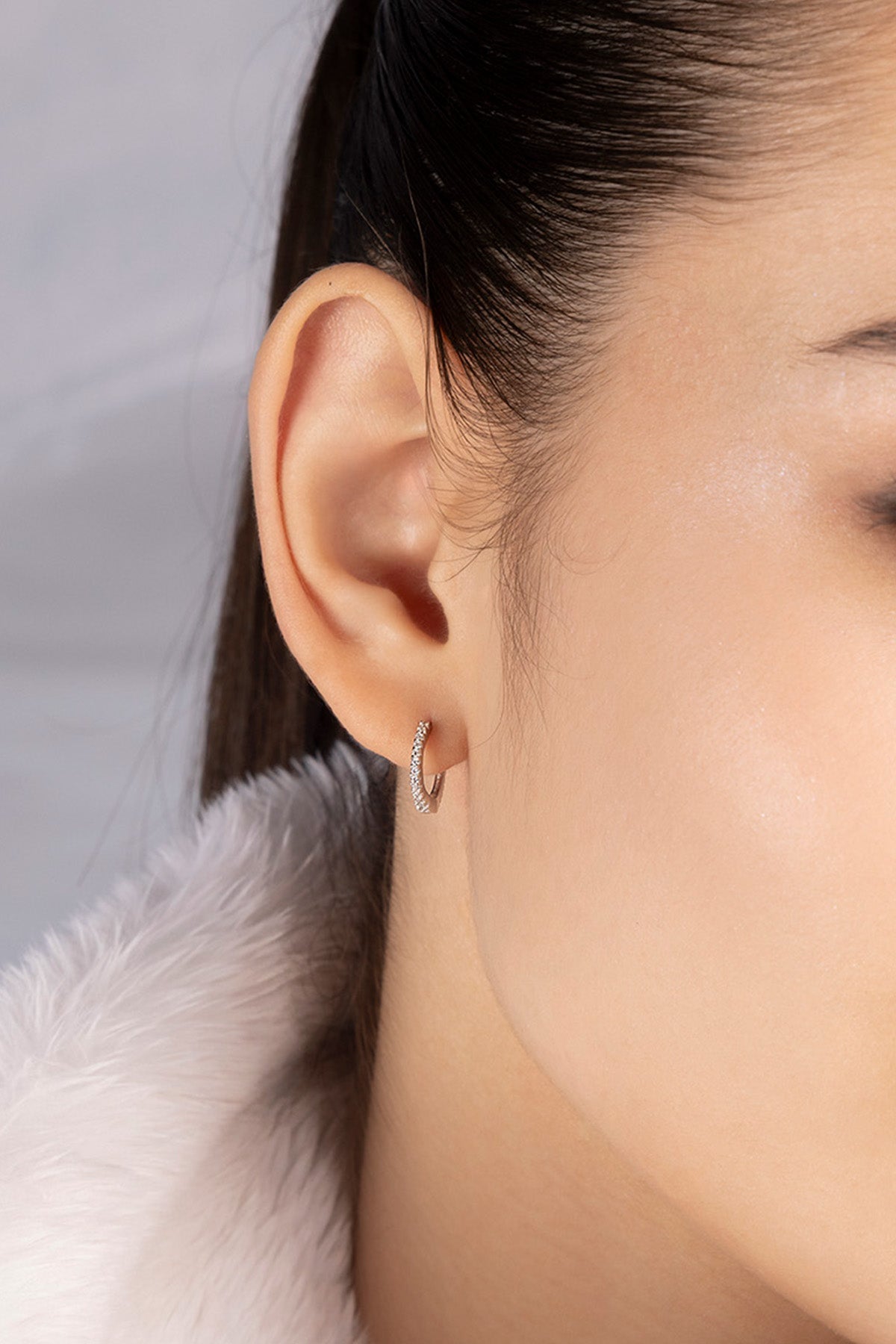 Close-up of a woman's ear wearing a 8.5mm paved hoop earring in silver from APM MONACO