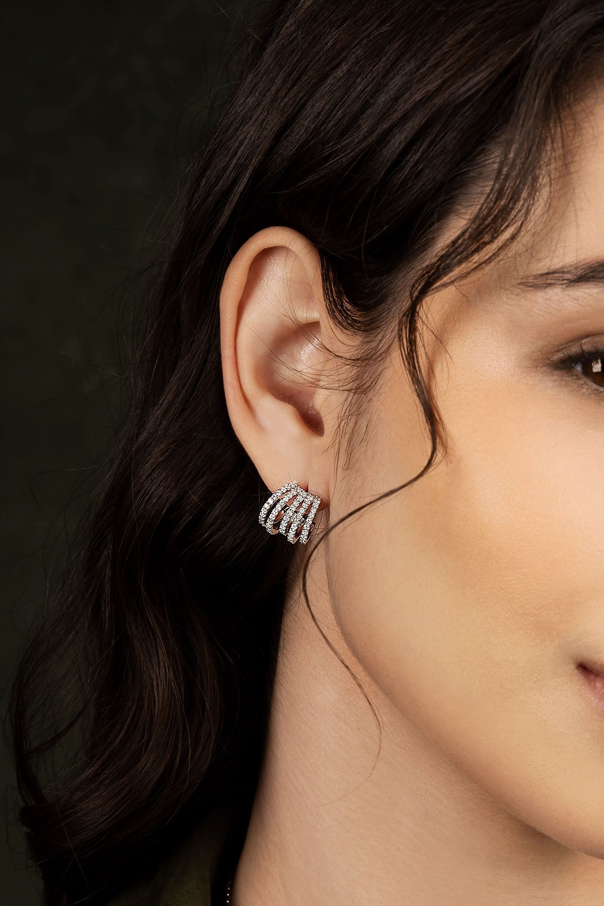 Close-up of a woman wearing a silver earring with a dark background