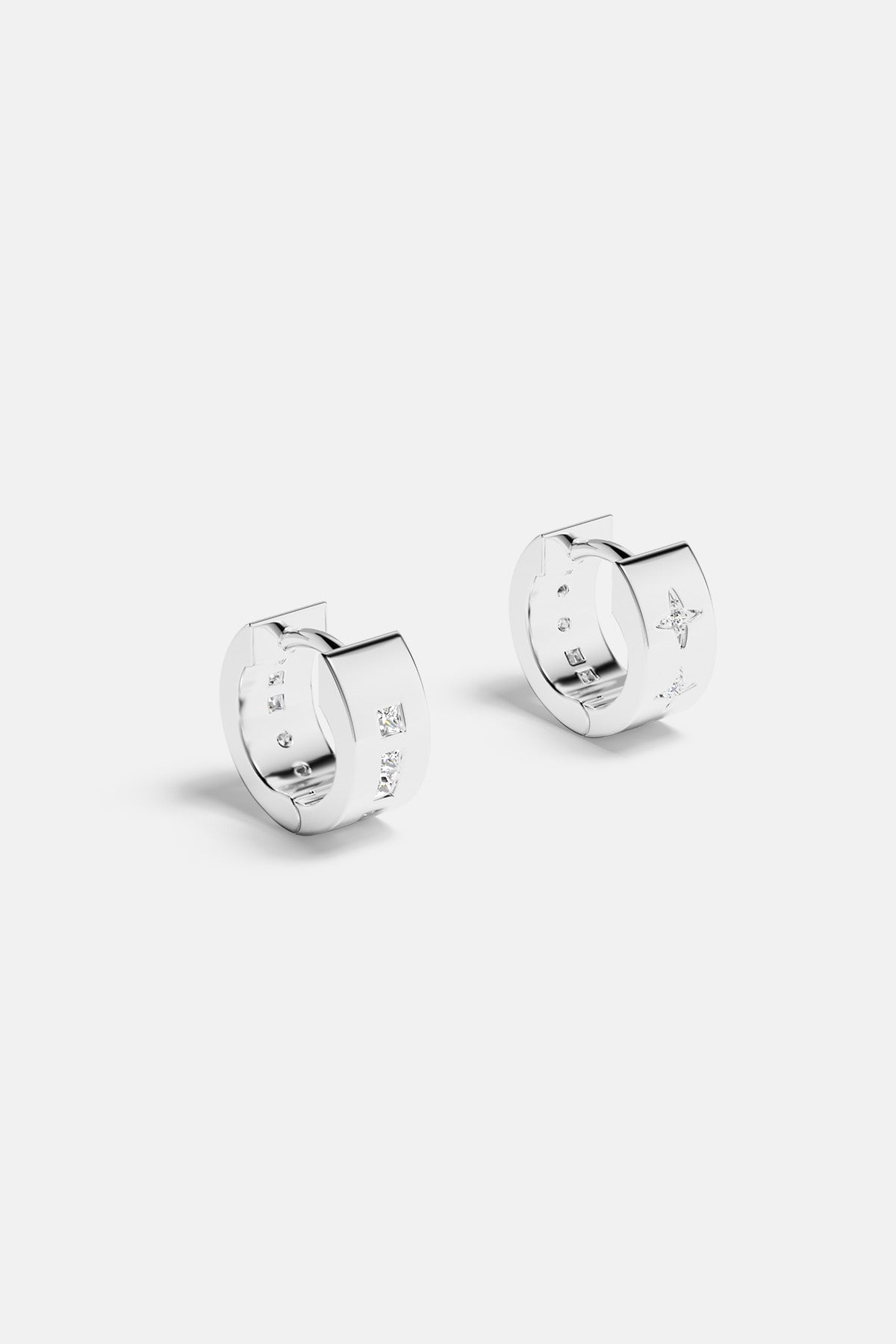 Earrings APM Monaco: small white huggie hoops with four to five gemstones along the outer surface.