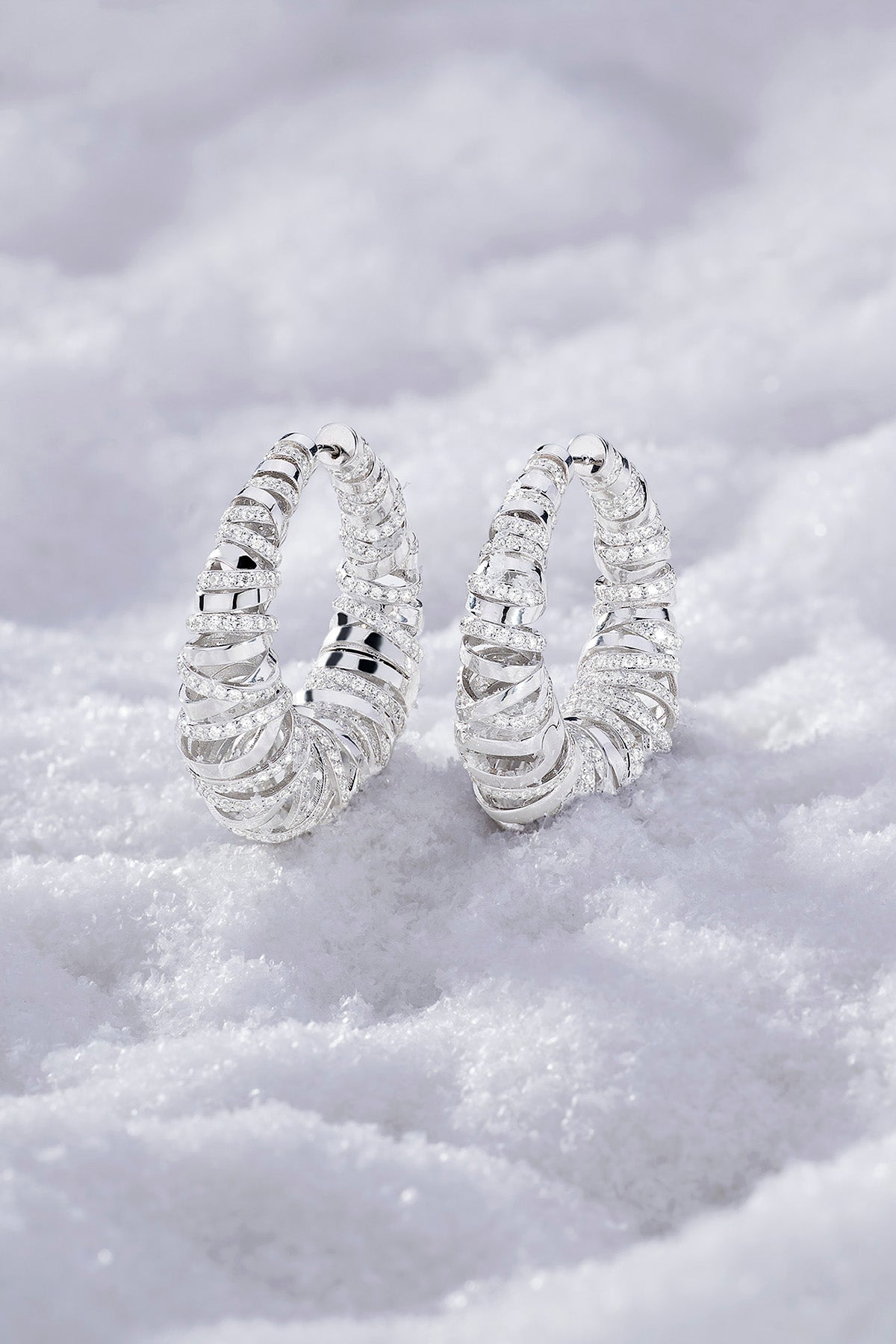 APM MONACO enlace hoop earrings in silver on a soft white surface