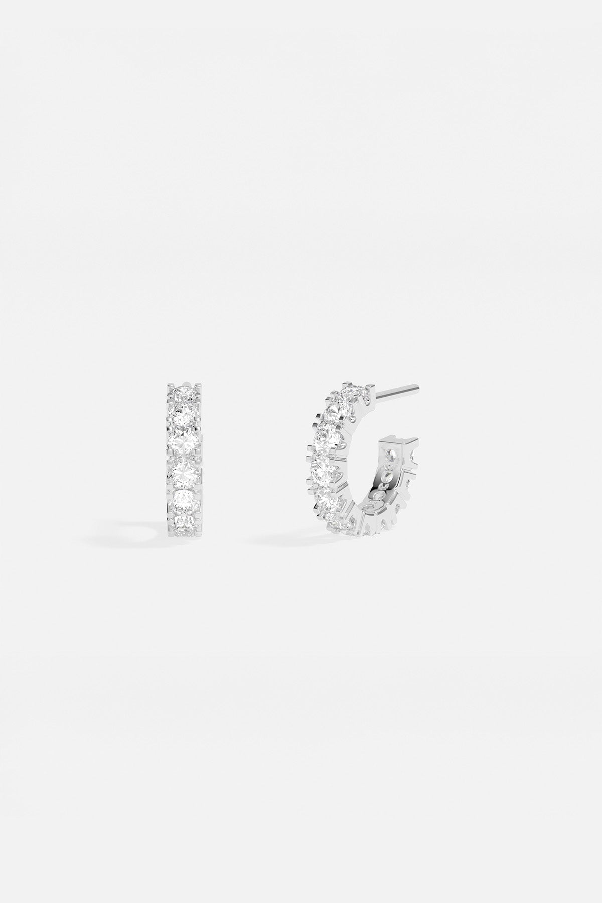 Earrings APM Monaco white stones-studded semi-circular huggie hoops.