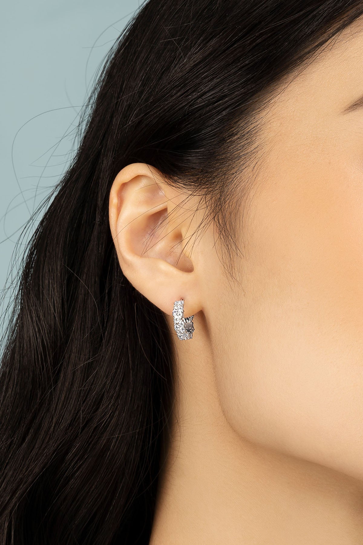 APM Monaco Drop Huggie Earrings in silver worn on ear