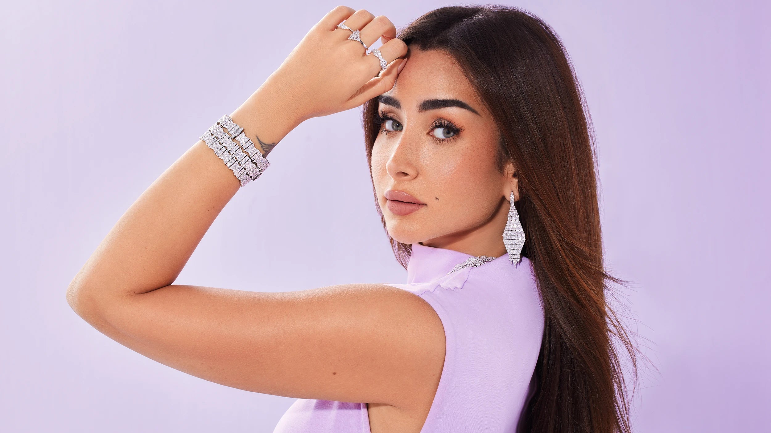 Hannah in a light purple outfit with APM MONACO Geometric jewelry set in silver with white stones against a light purple background