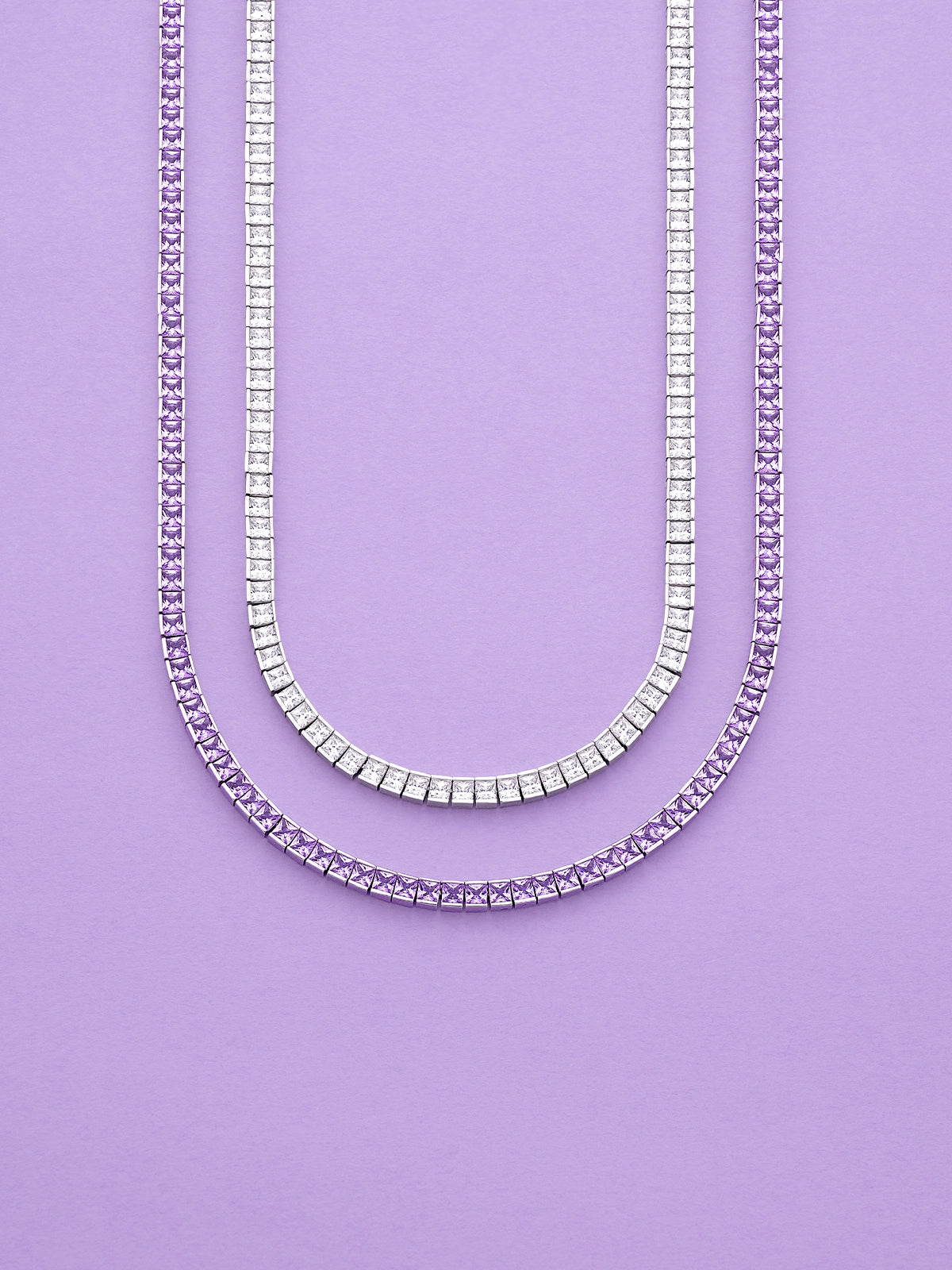 Two APM MONACO Printemps necklaces in silver and purple on a purple background