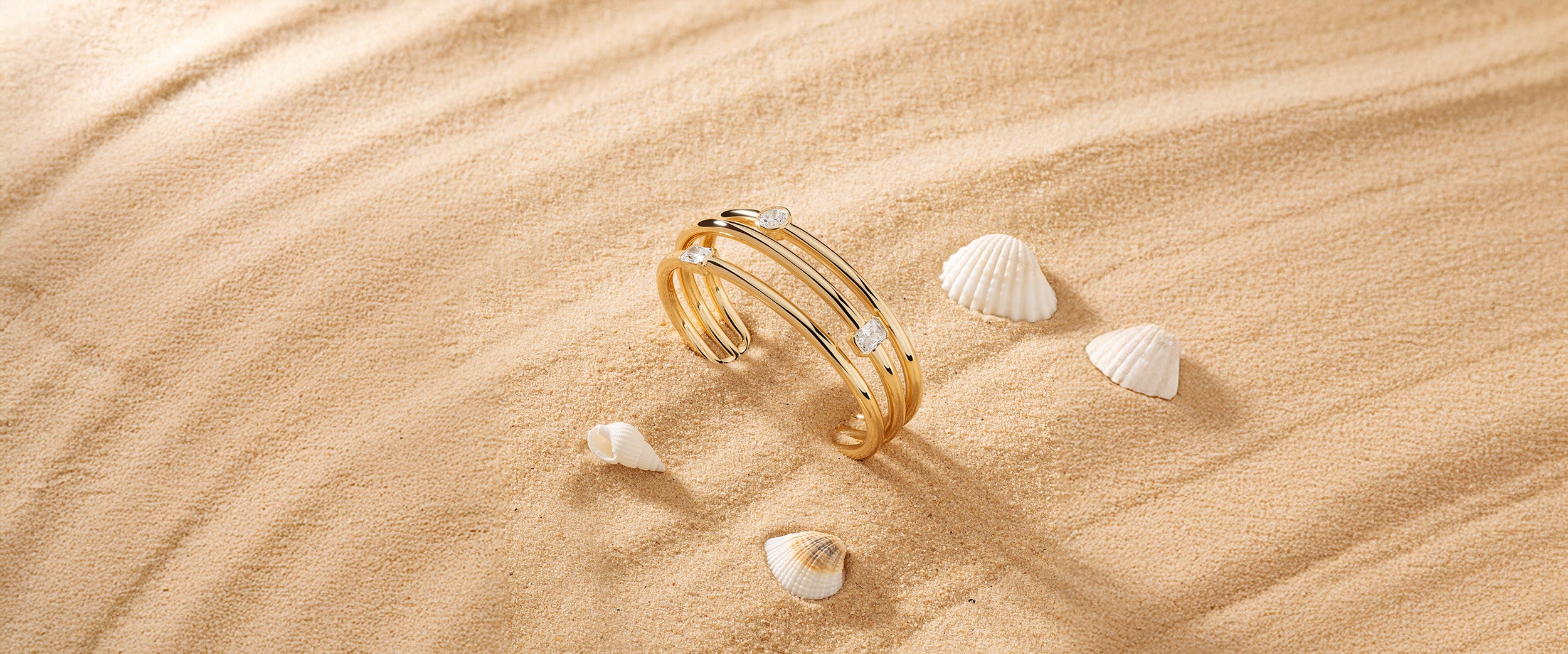 Triple gold plated bracelet with pave details and seashells on sand