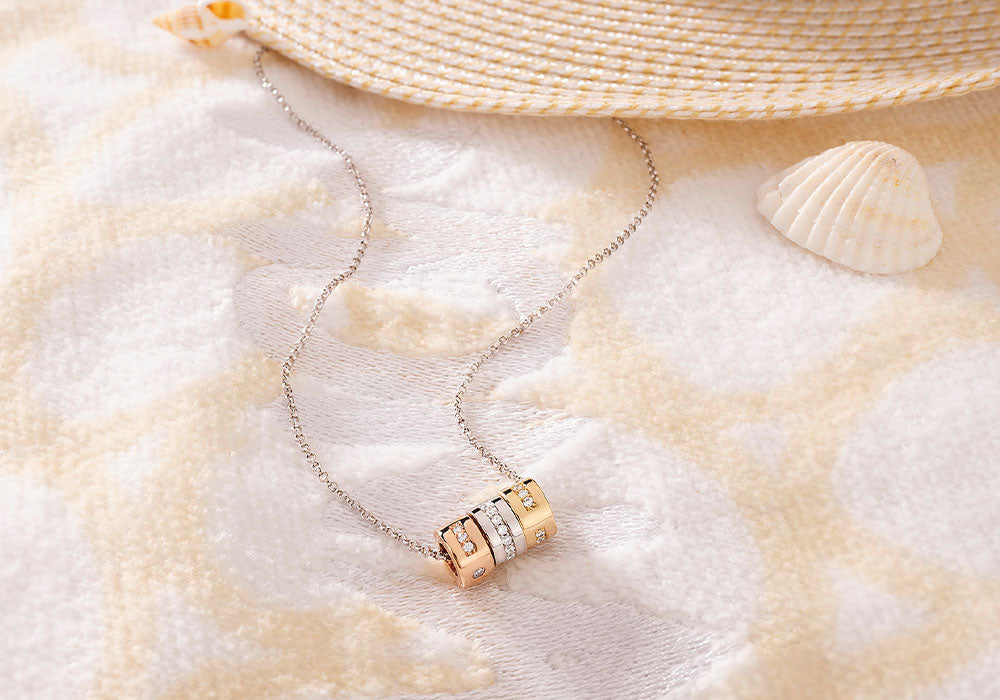 Necklace with gold and silver pendants with pavé details with a straw hat and shell