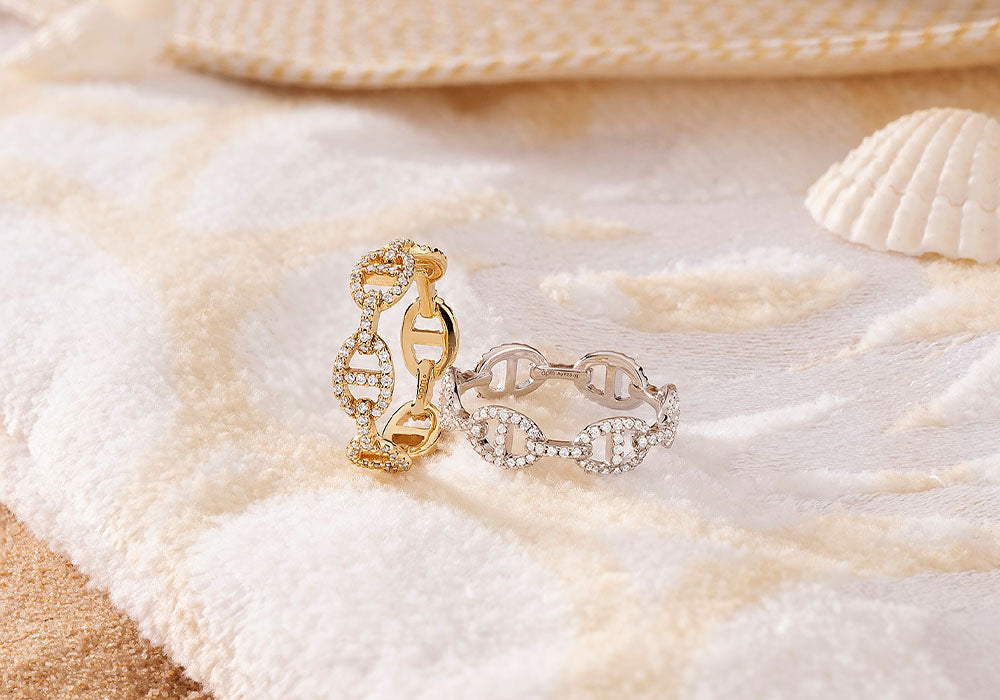 Gold-plated & sterling silver Maille Marine rings with pavé details on a textured surface with shells