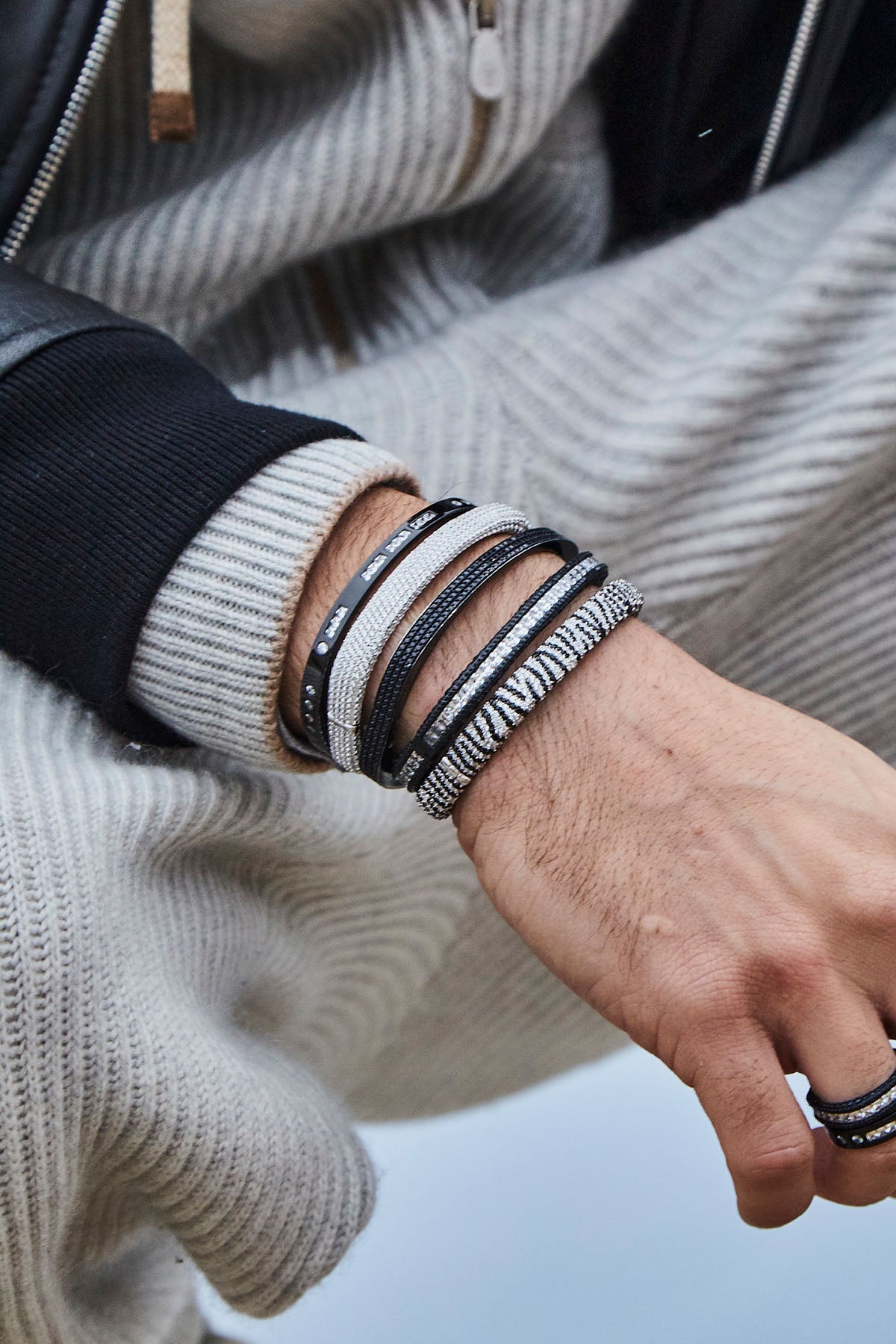 Close-up of a person's wrist wearing multiple bracelets with pavé details