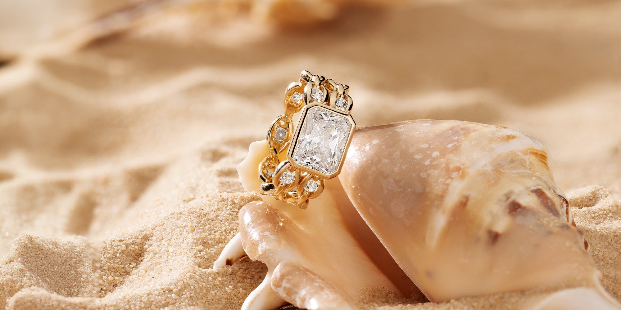 Gold-plated ring with pavé accents on a seashell in sand
