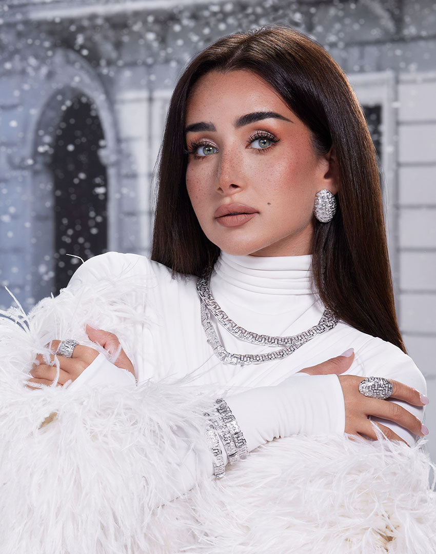 Woman in a white outfit with jewelry against a snowy background