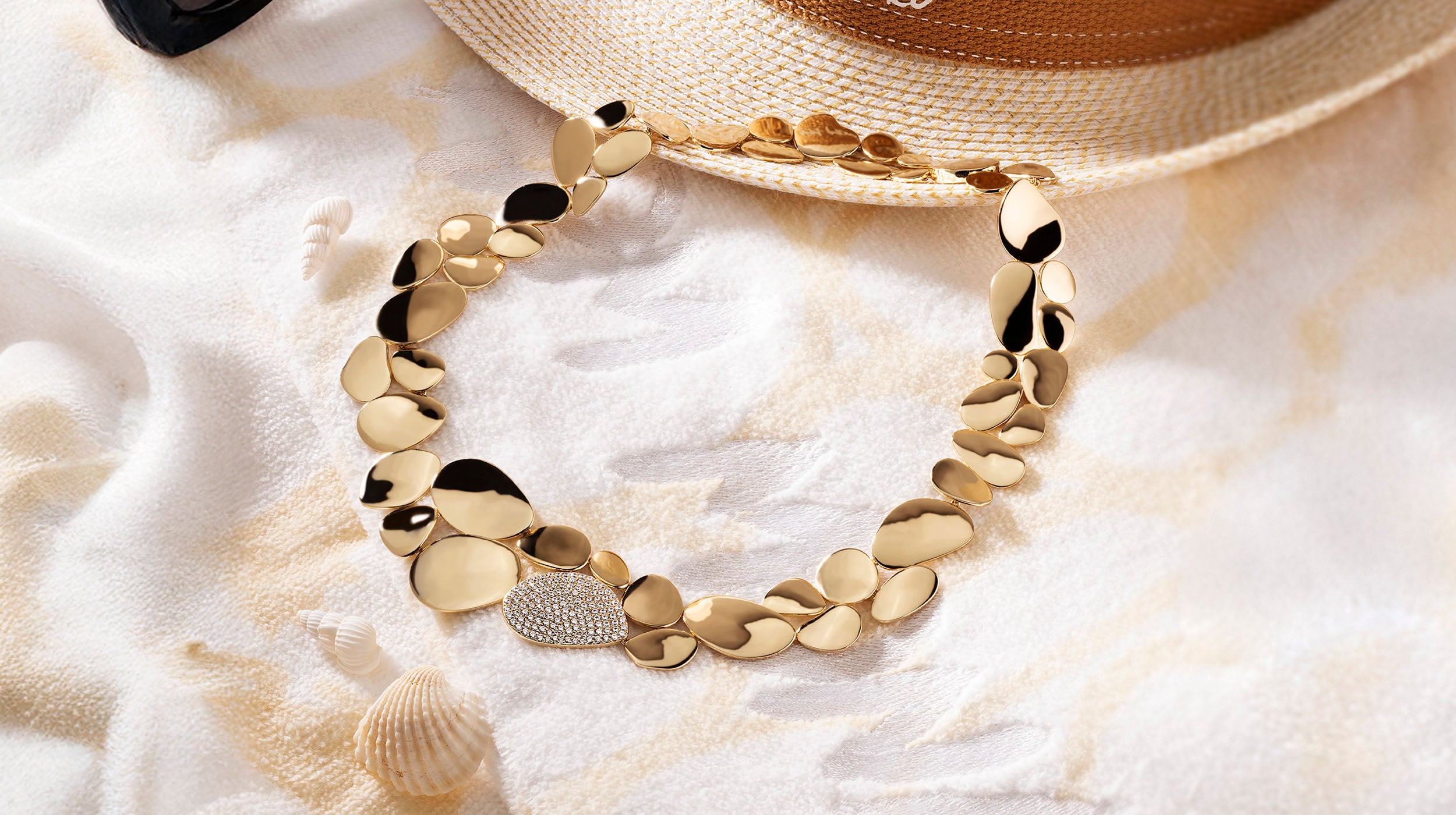 yellow gold necklace from APM MONACO soleil on a sandy background