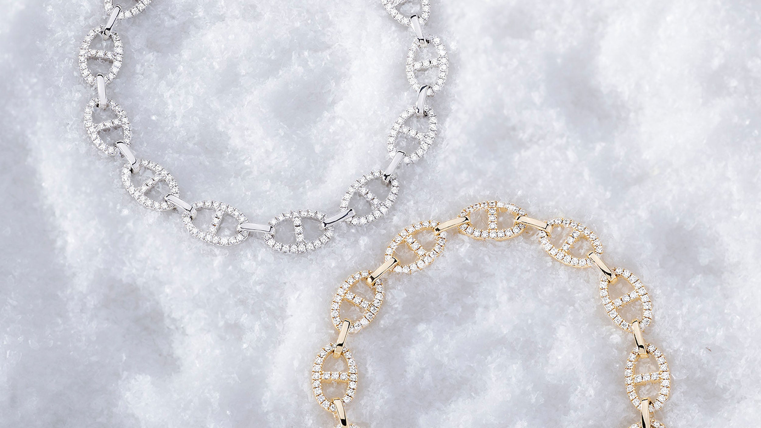 Two yellow gold and silver necklaces from APM MONACO yacht club, on a textured white background