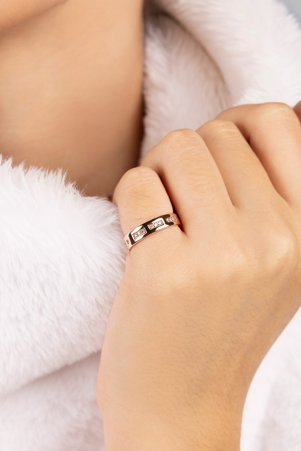 Hand wearing a ring with a white fur background