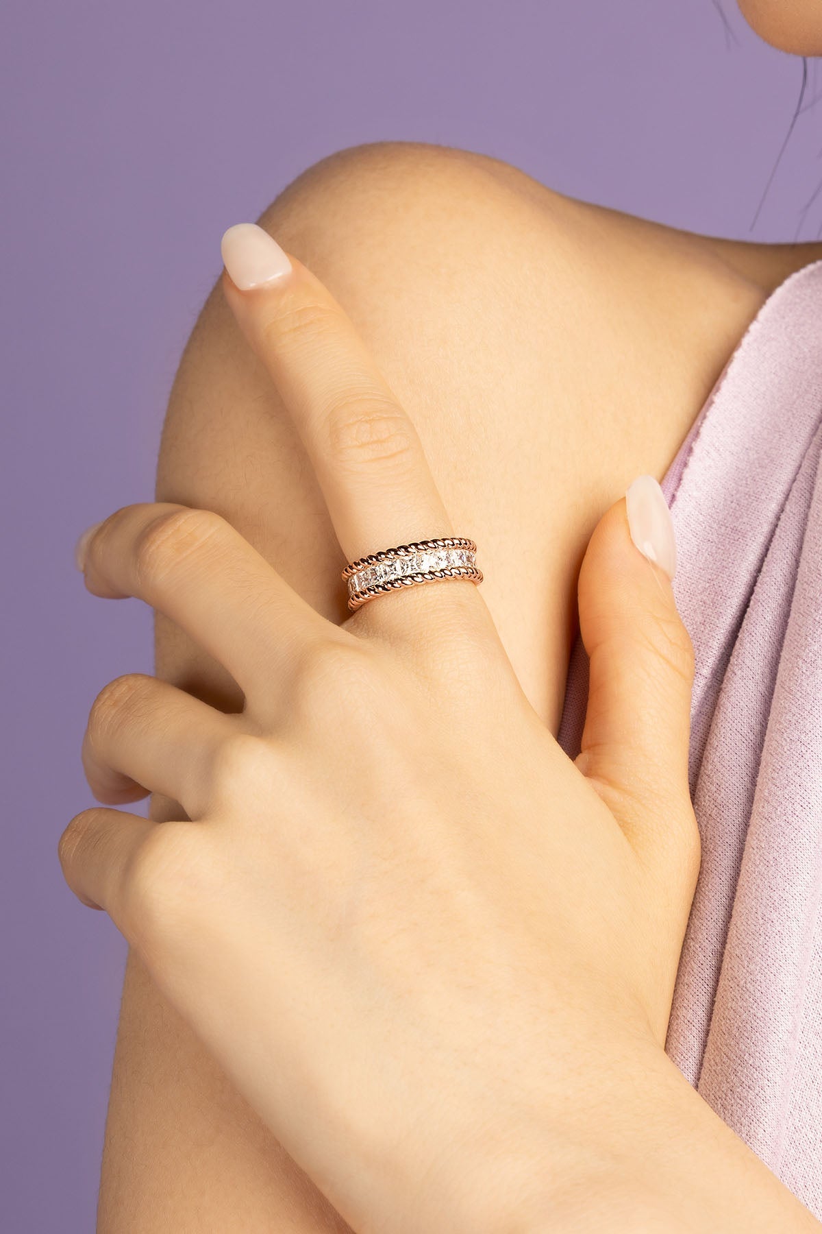 Close-up of a hand wearing a zirconia stones ring on a purple background