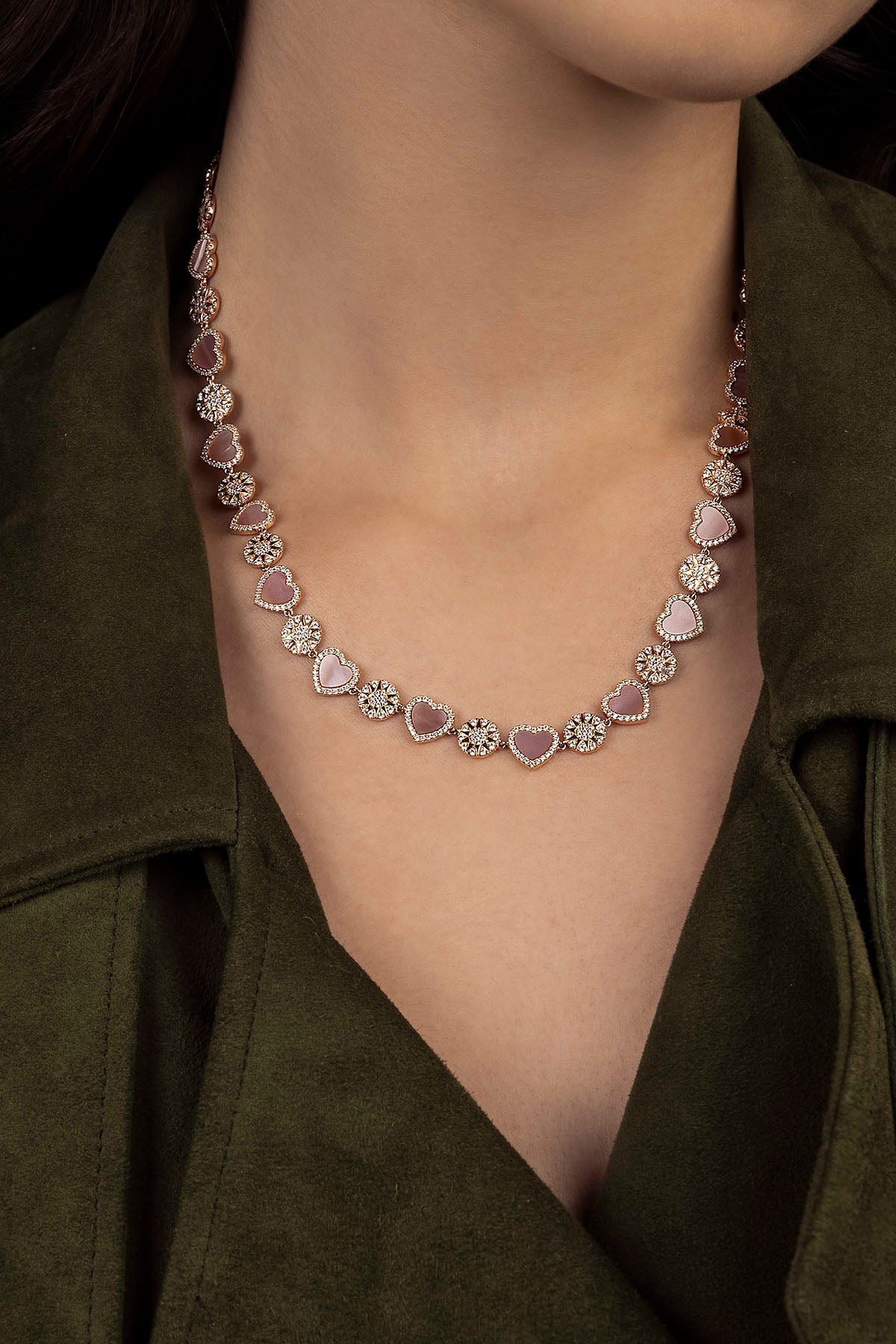 Heart-shaped necklace worn by a person against a dark background