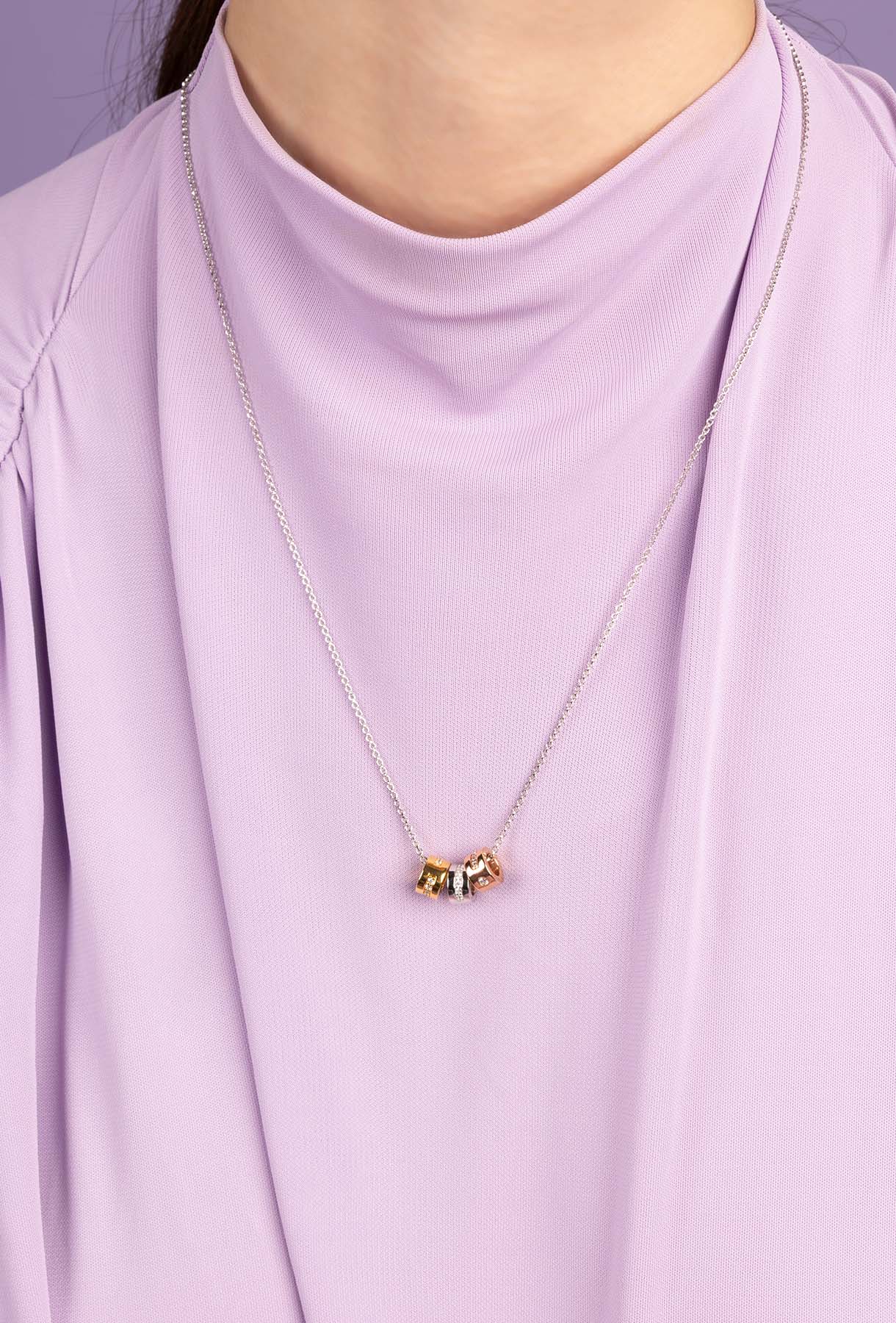 Necklace with a small pendant on a person wearing a light purple top.
