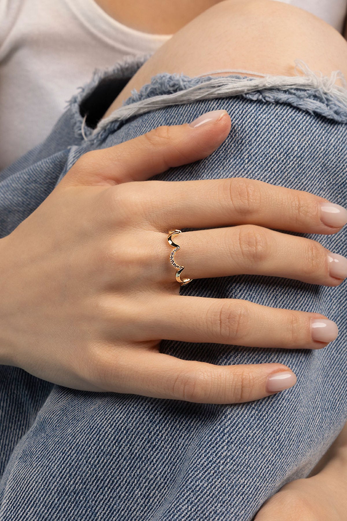 Close-up of a hand wearing a ring with denim fabric in the background