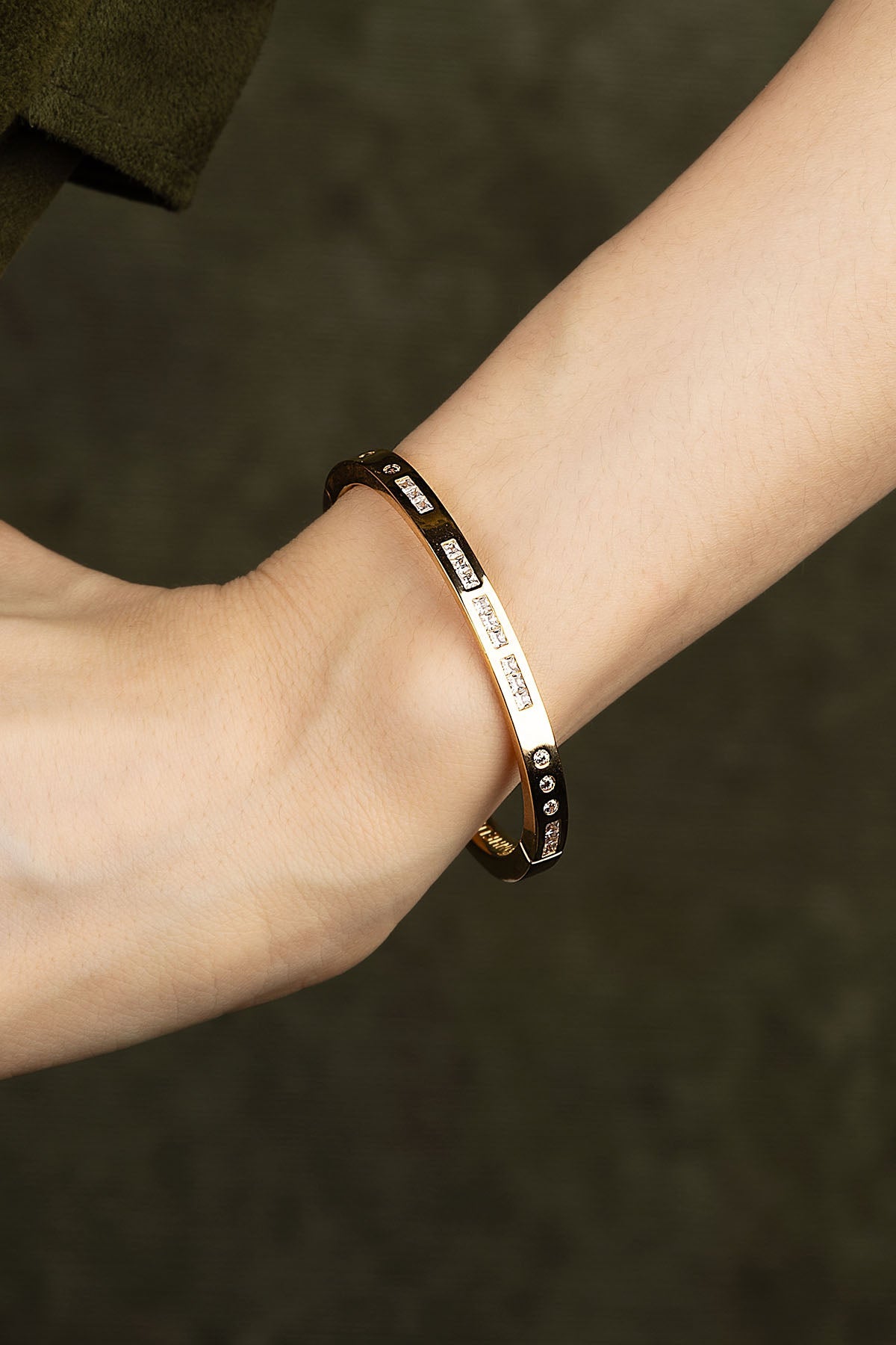 Bracelet on a wrist with a dark green background