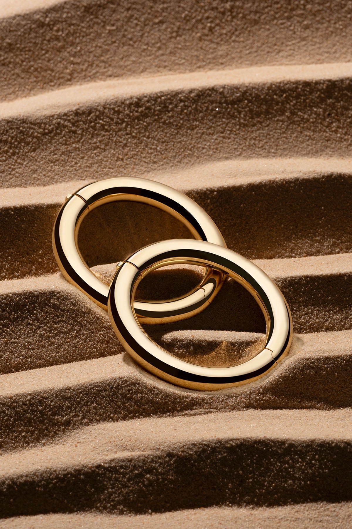 APM Monaco Bold Bangle in yellow gold on soft beach